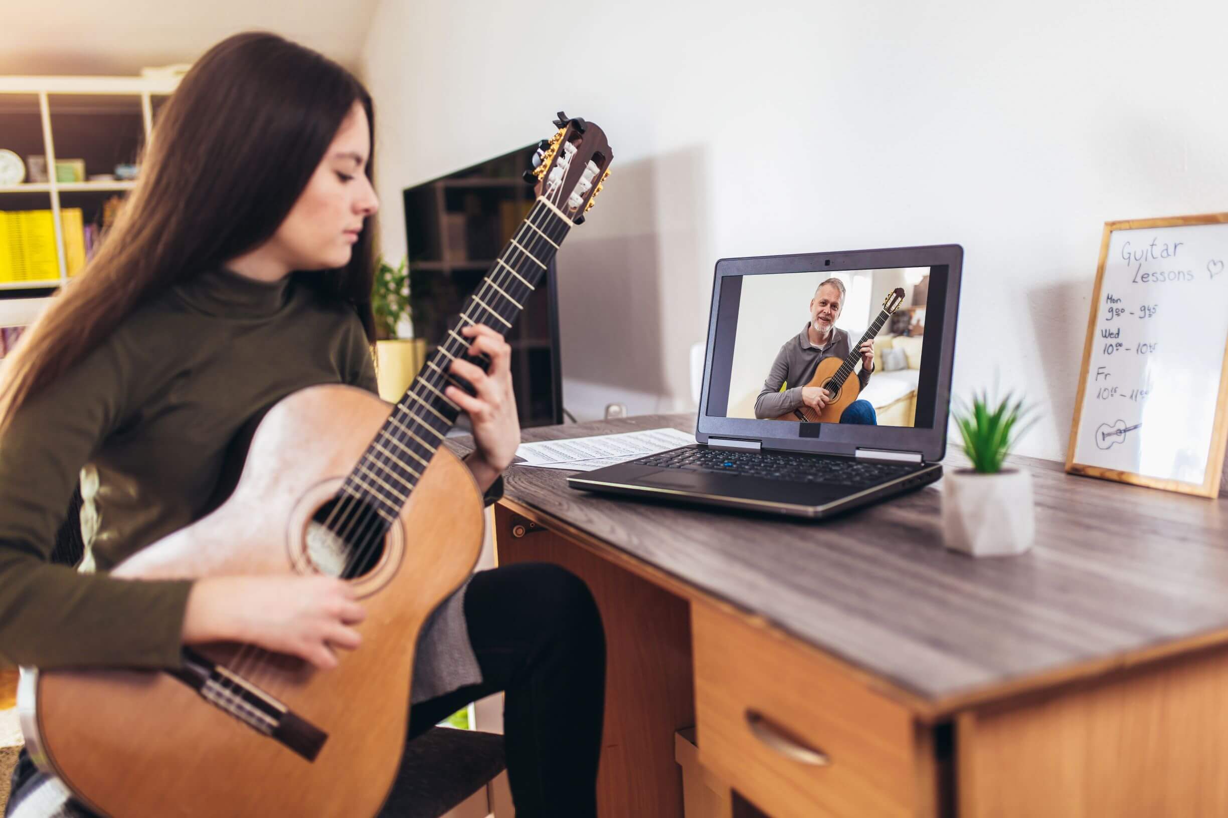 Image shows a girl learning guitar through a video.