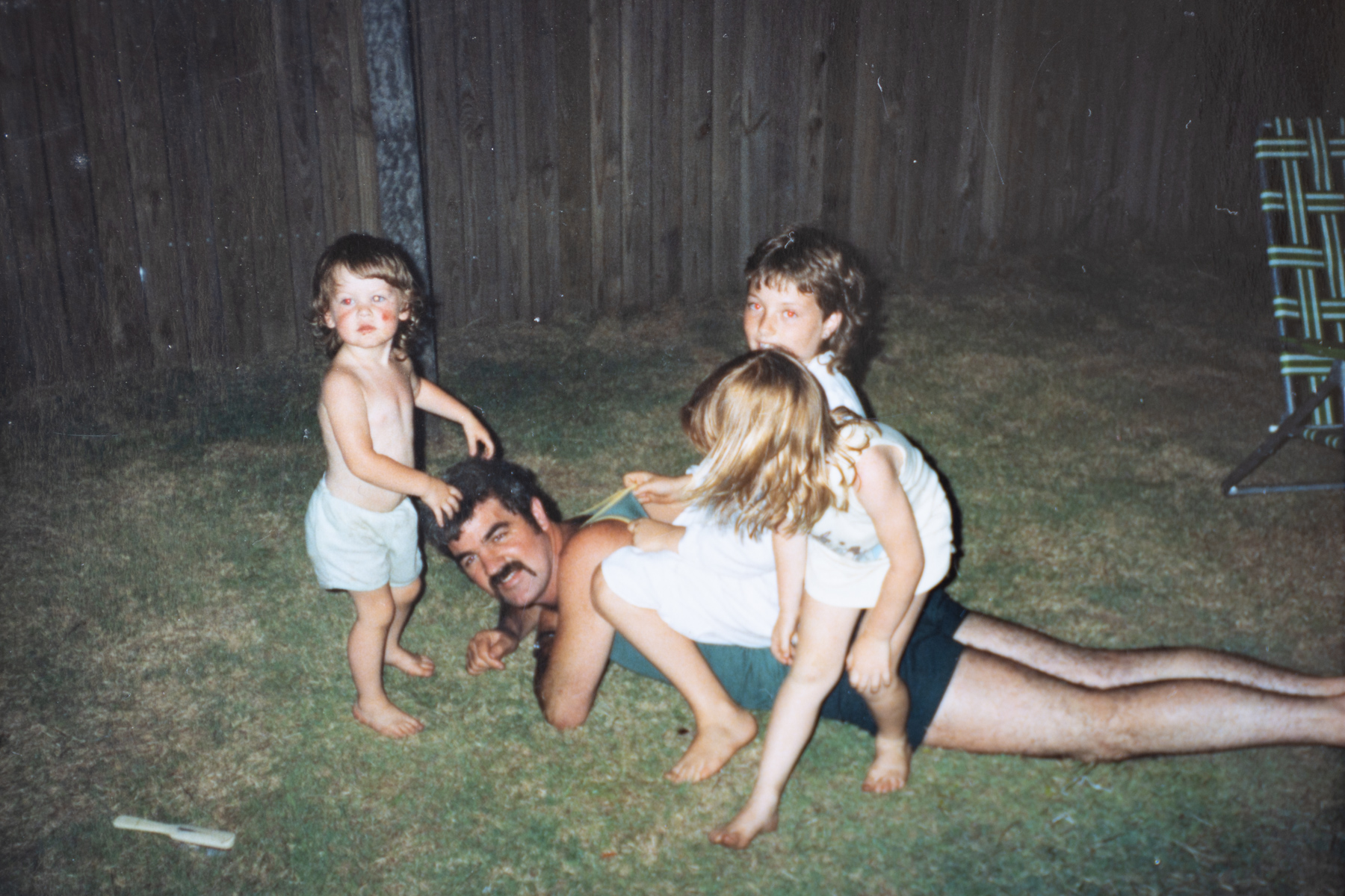 Photo of Rod laying in the grass with 3 of his children on his back