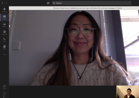 Teams call between Letitia and Isabel. Letitia has glasses on and is wearing a cream coloured knit jumper. She has earphones in. Isabel is wearing a white shirt and brown jacket. Both are smiling at the camera.