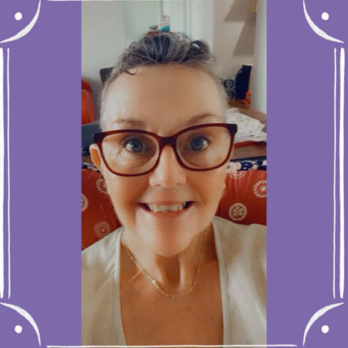 A purple background with a frame of straight white lines and curved corners, in the middle is a selfie photo of Annett beaming at the camera. She is a white woman with short dark grey hair swept back over her forehead, red glasses framing her eyes.