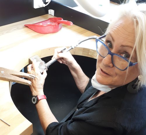 A woman with blonde hair and glasses working with tools.