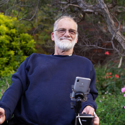 Photo shows Trevor outdoors. He is an elderly man with a grey beard, sitting in a wheelchair.